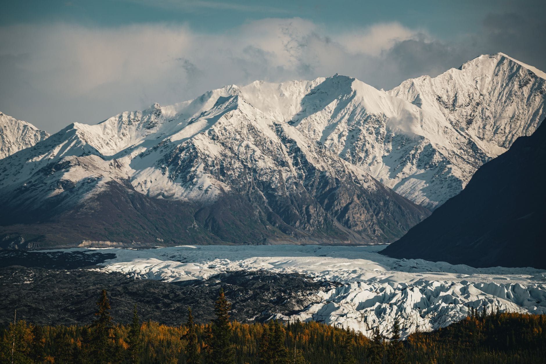Panoramic view of Matanuska Glacier sprawling beneath rugged snow-covered Chugach mountains in Alaska.